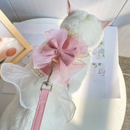 chat blanc sur une table porte un  Harnais pour chat rose en tutu