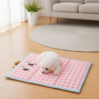 Petit chien blanc couché sur son tapis rafraichissant à carreaux roses